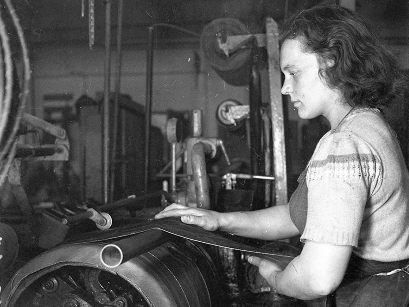 (imagem antiga em preto e branco de mulher em fabrica de pneus)